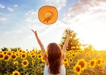 Girl throws strawhat in the air in nature